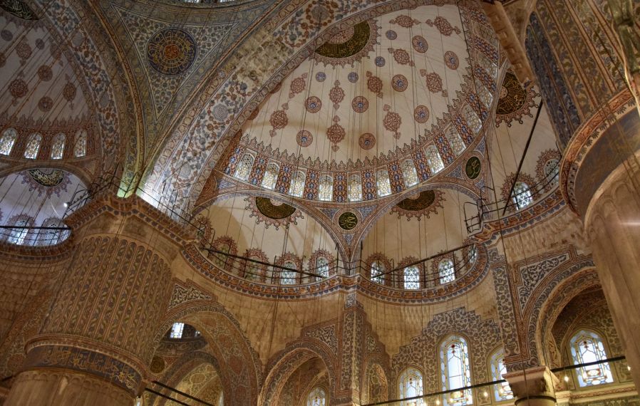 A view upwards towards the domes of a mosque, taking in all the intricate artistic details.