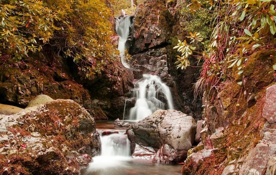 Photograph of a waterfall and autumn trees in Tollymore Forest Park.