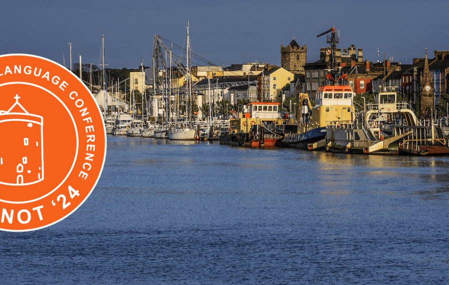 Photograph of boats along a river that runs through the city of Waterford with an orange version of the 2024 Celtic Knot logo