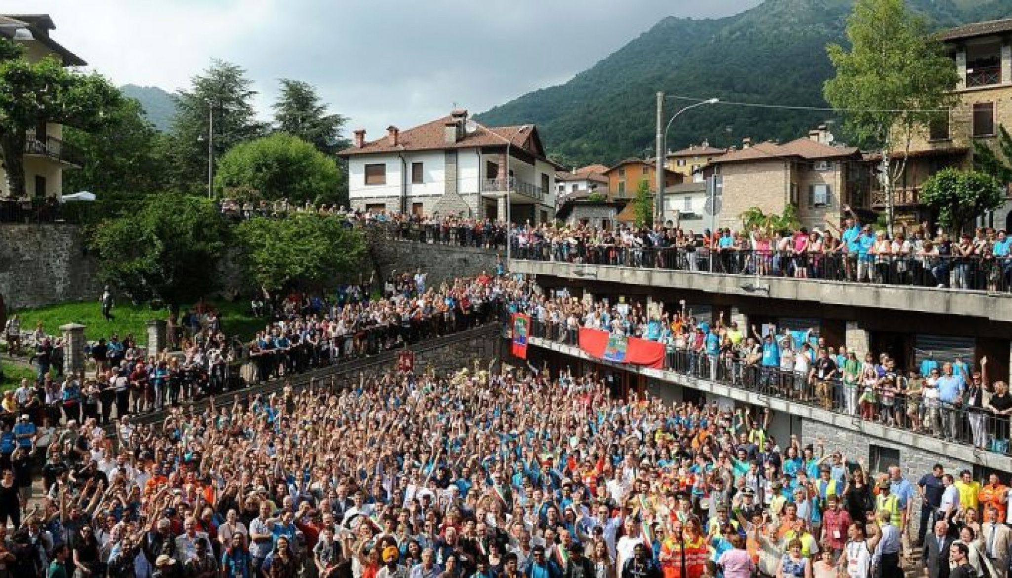 A large crowd gathered for a group photo in a hillside village