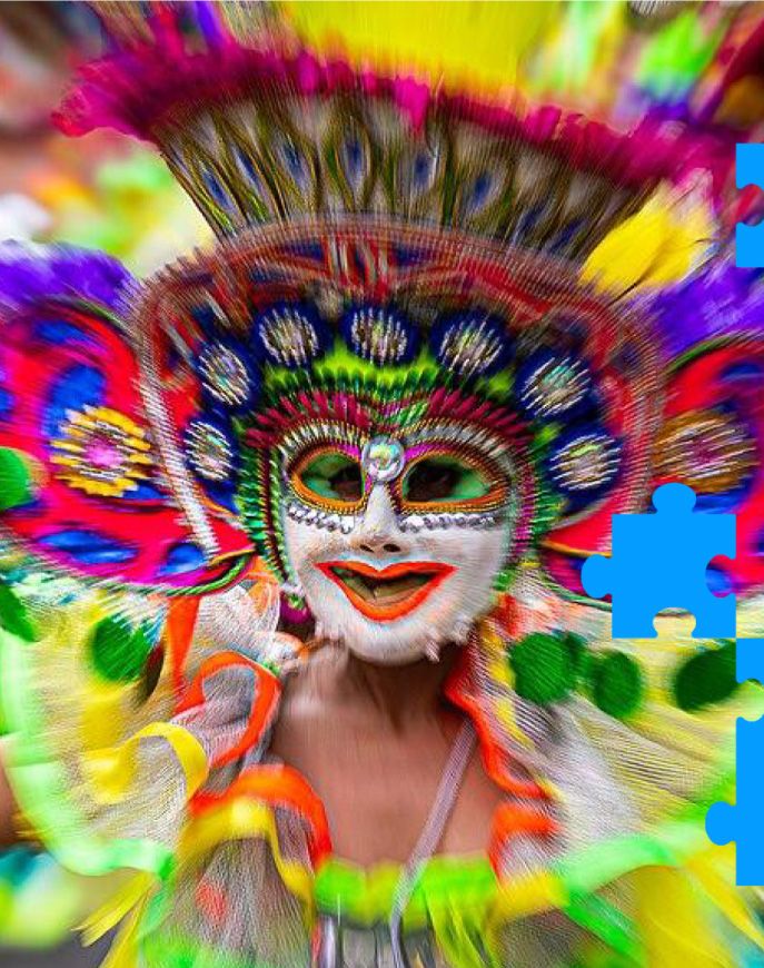 Performer in a colourful smiling mask and feathered headdress at a festival.