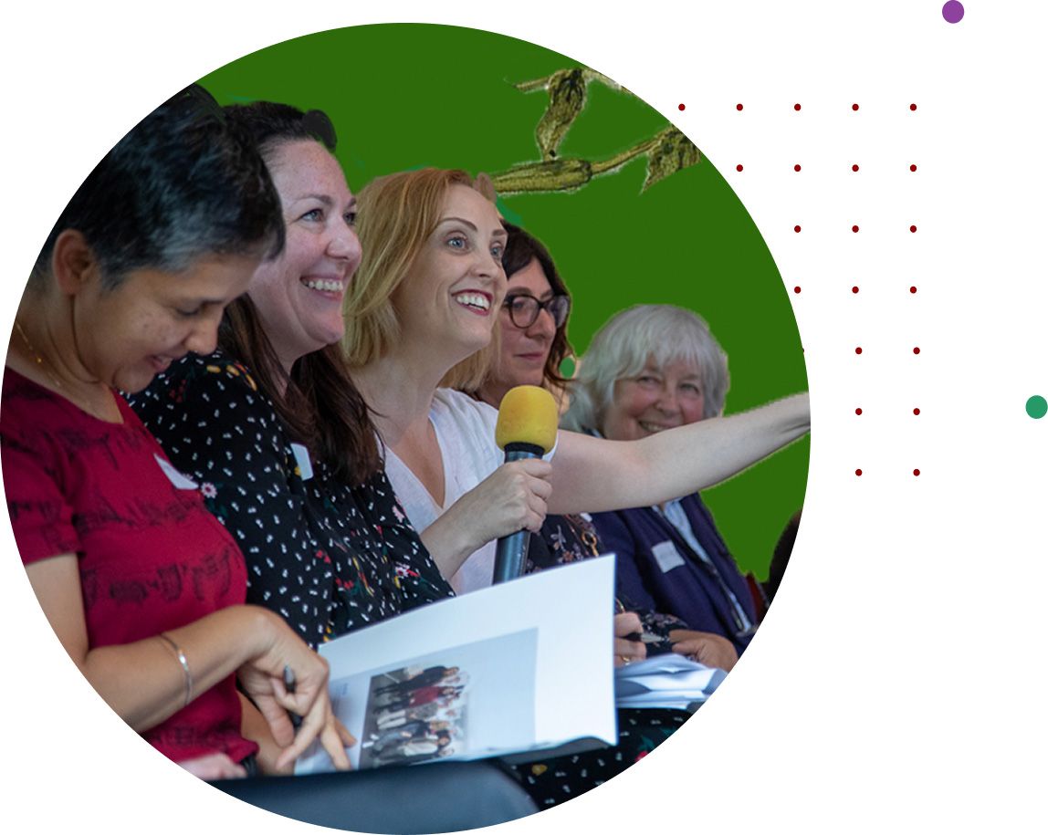 Women smiling at a panel event as one speaks into a microphone