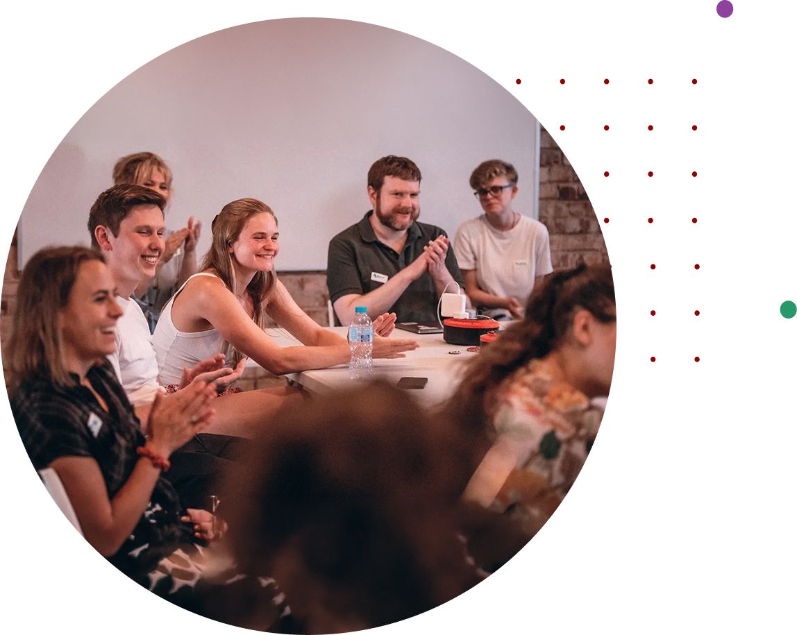 People smiling and clapping around a table at a community event.
